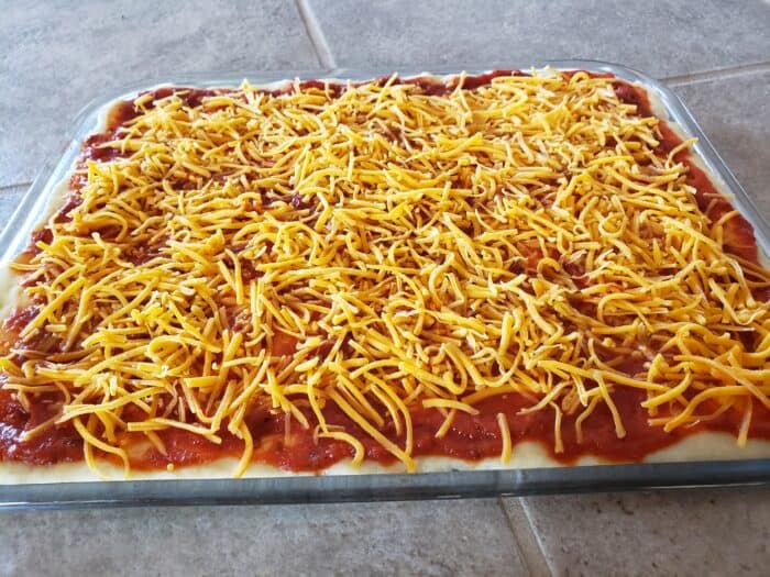 pizza crust with pizza sauce and cheddar cheese