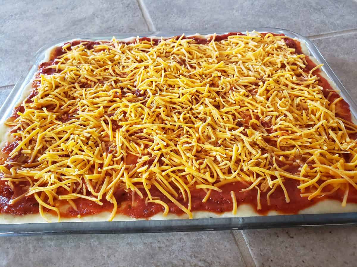 Add the sharp cheddar cheese over the pizza sauce and pizza crust.