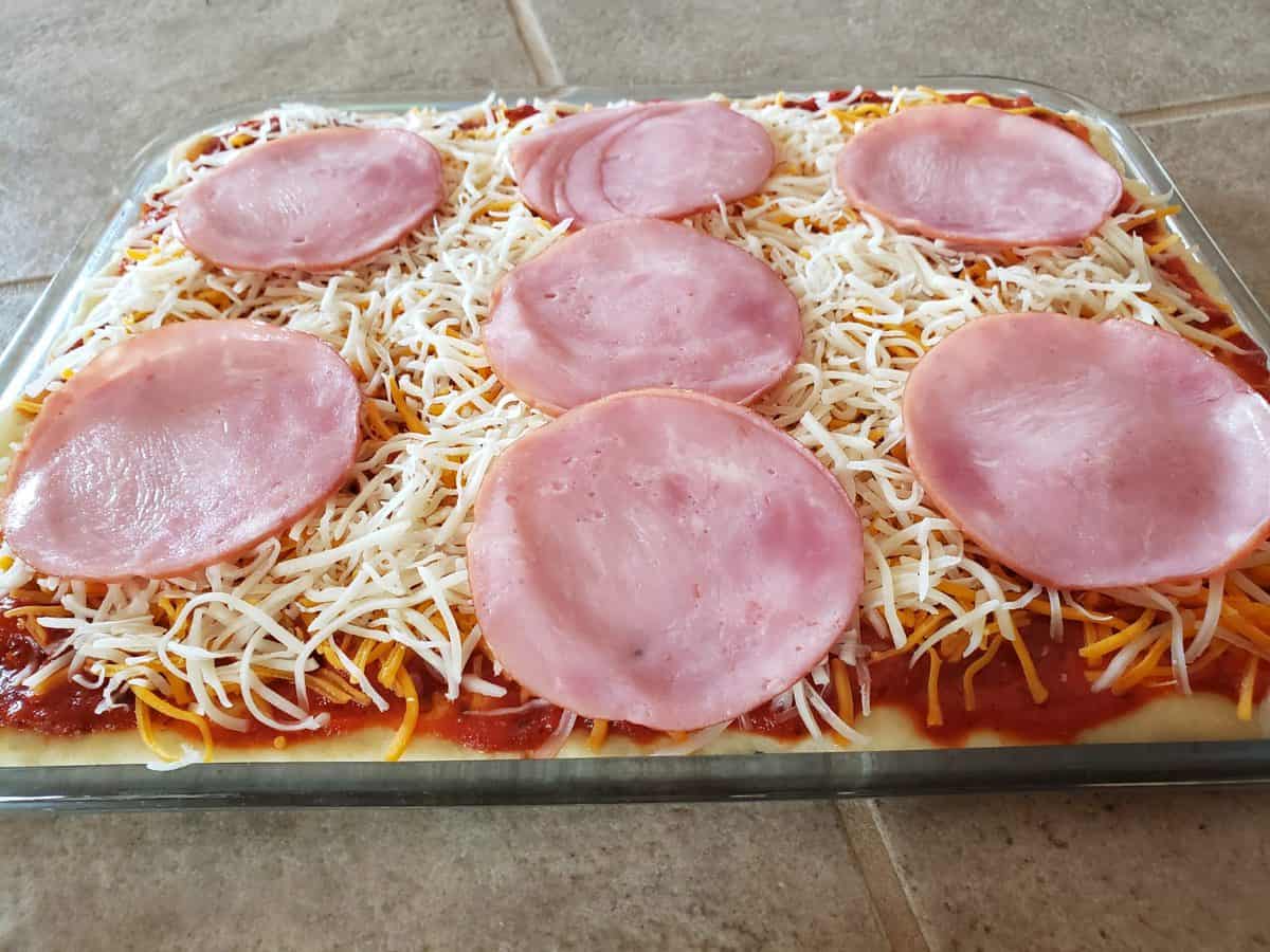 Add the smoked Canadian bacon to the pizza.