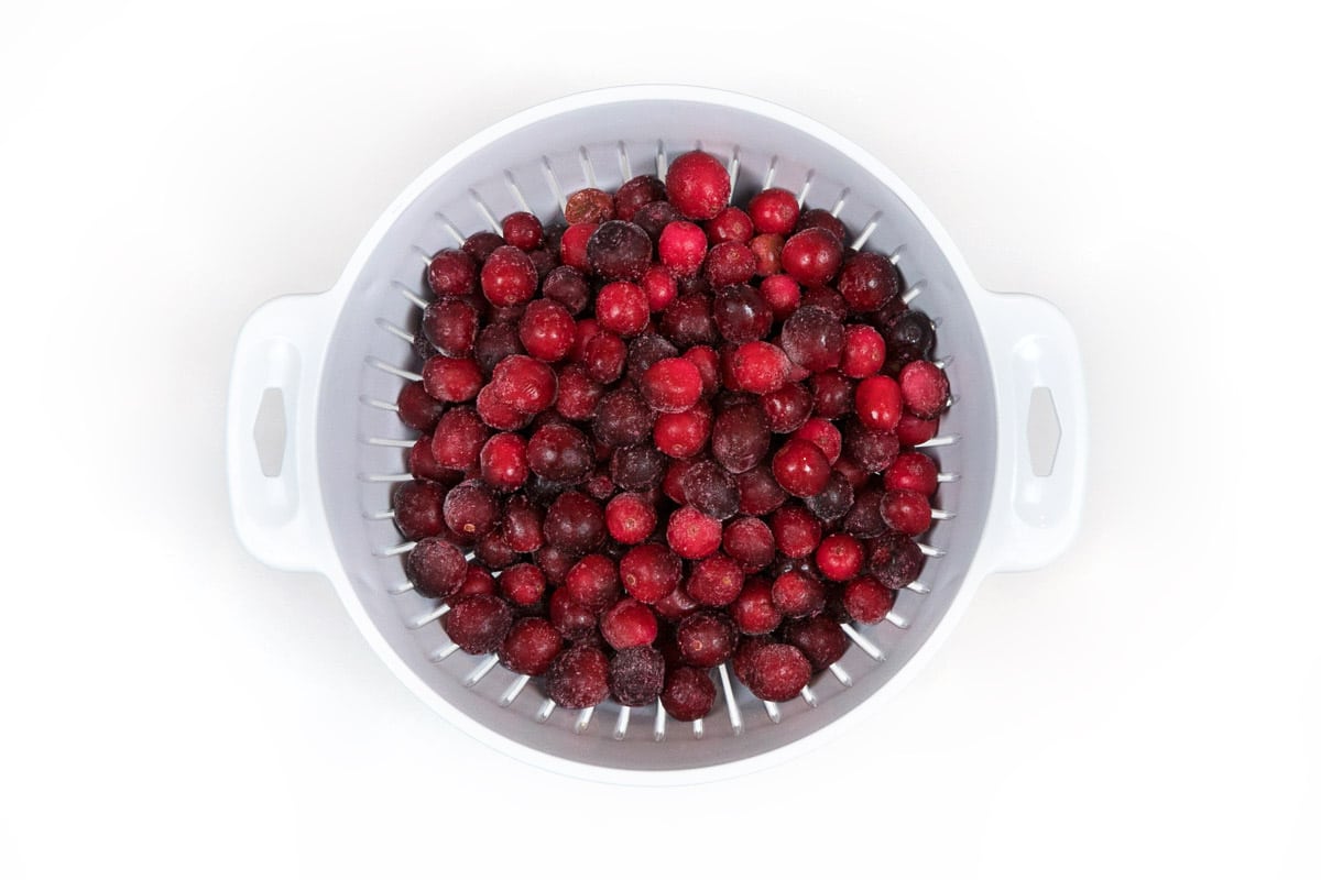 Rinse the frozen whole cranberries in a colander.