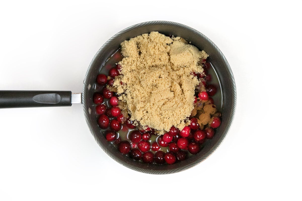 The brown sugar, orange juice, water, ground cinnamon, and vanilla extract are added together with the whole cranberries in the saucepan.