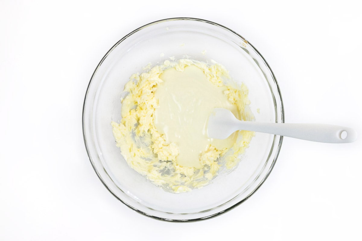 The melted white chocolate is added to the softened butter.