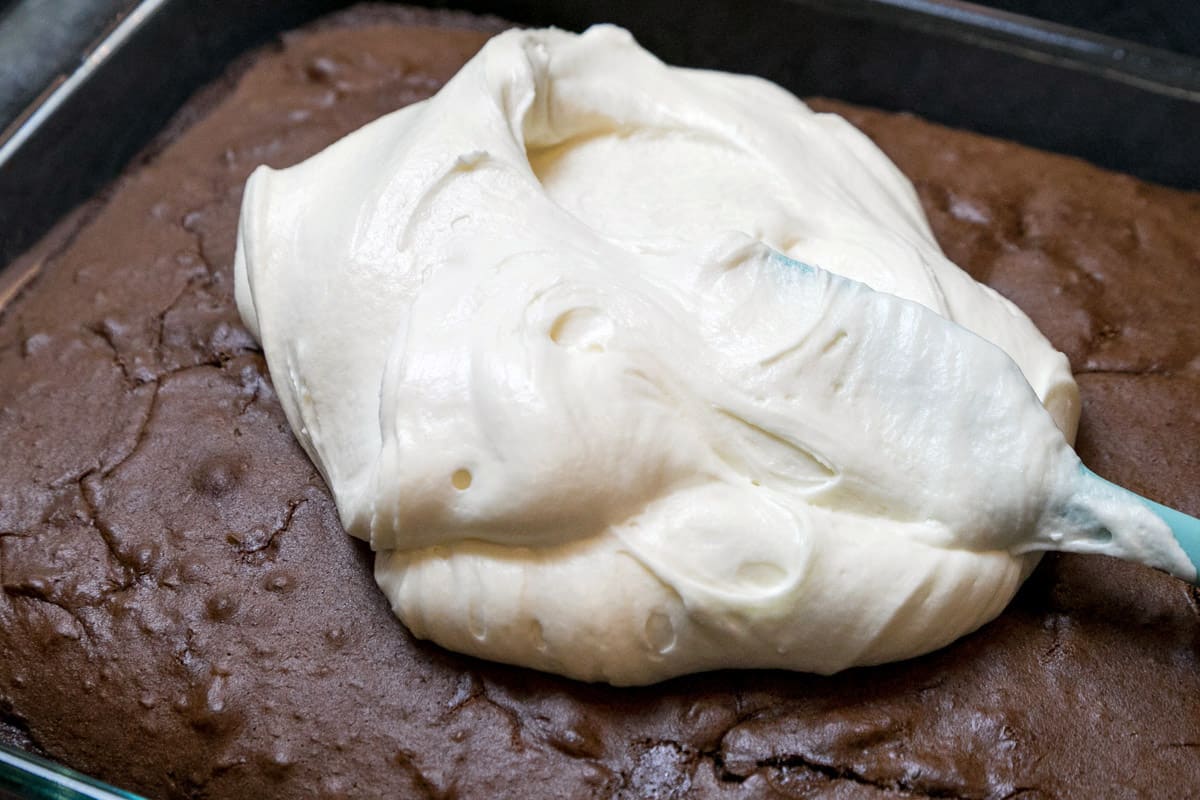 White chocolate buttercream frosting is spread on a chocolate cake.