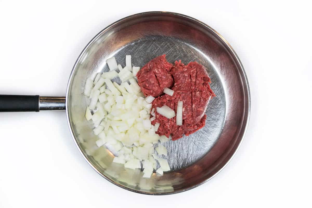 Lean ground beef and onions in a frying pan.