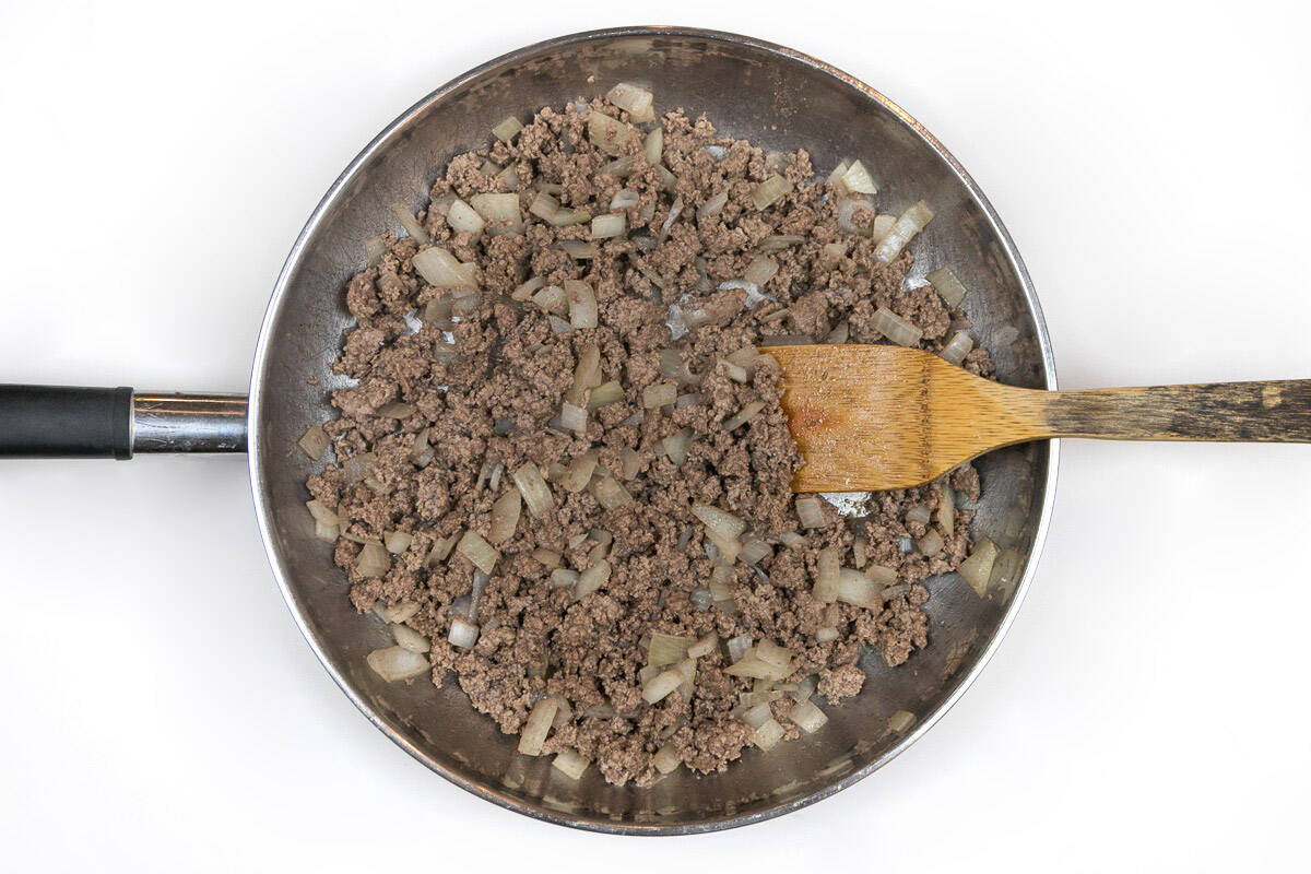 Browned ground beef and onions in a frying pan.