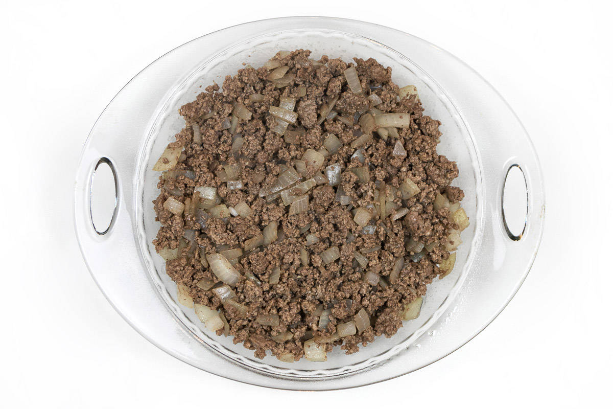 The lean ground beef mixture is poured into the pie dish.