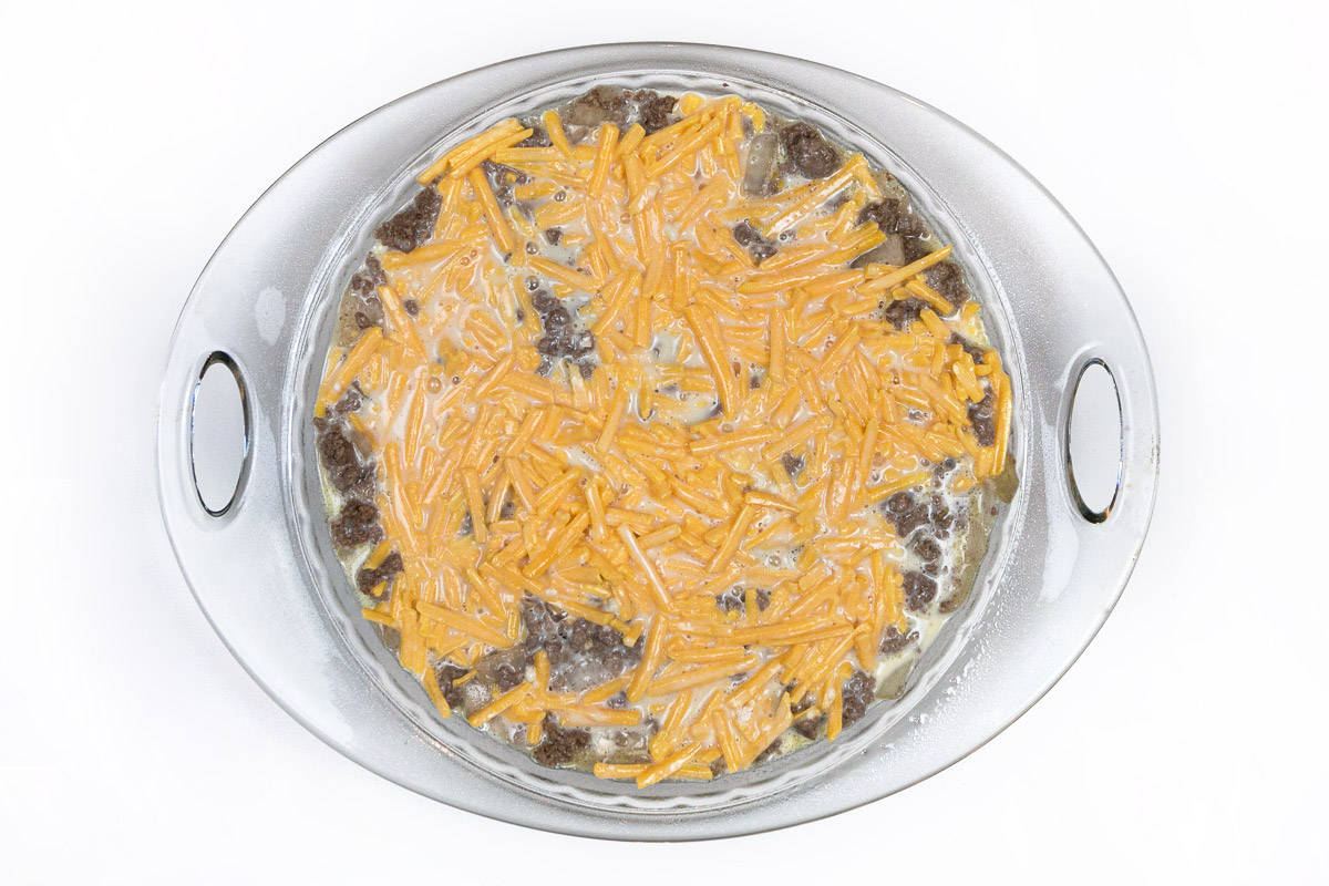 The Bisquick mixture is poured on top of the lean ground beef mixture in the pie dish.