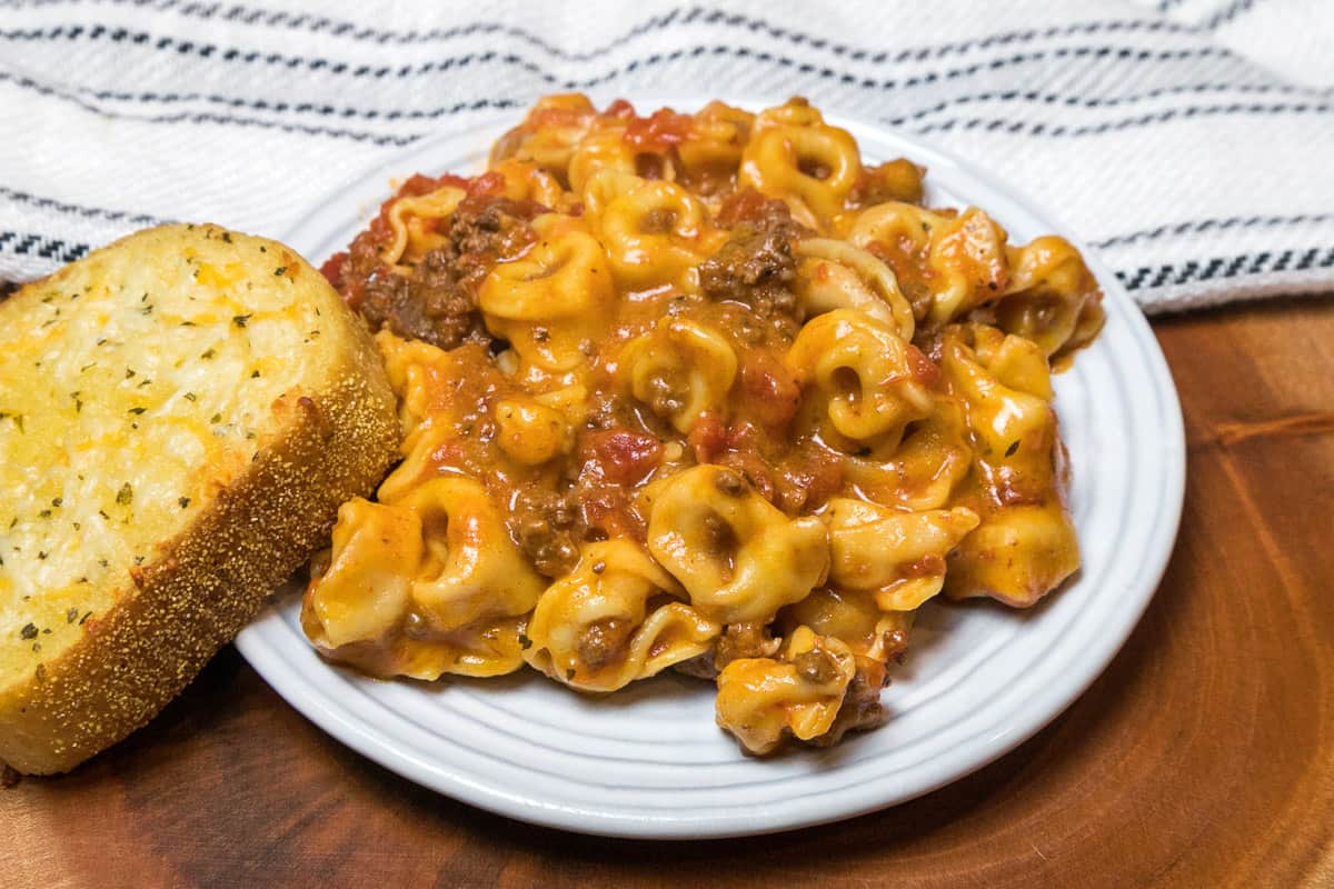 Cheesy Instant Pot tortellini on a plate with garlic bread.