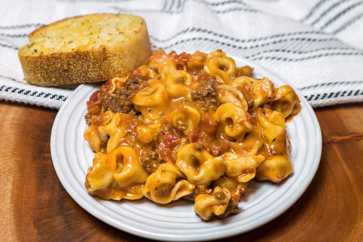 Cheesy Instant Pot tortellini on a plate with a piece of garlic bread.