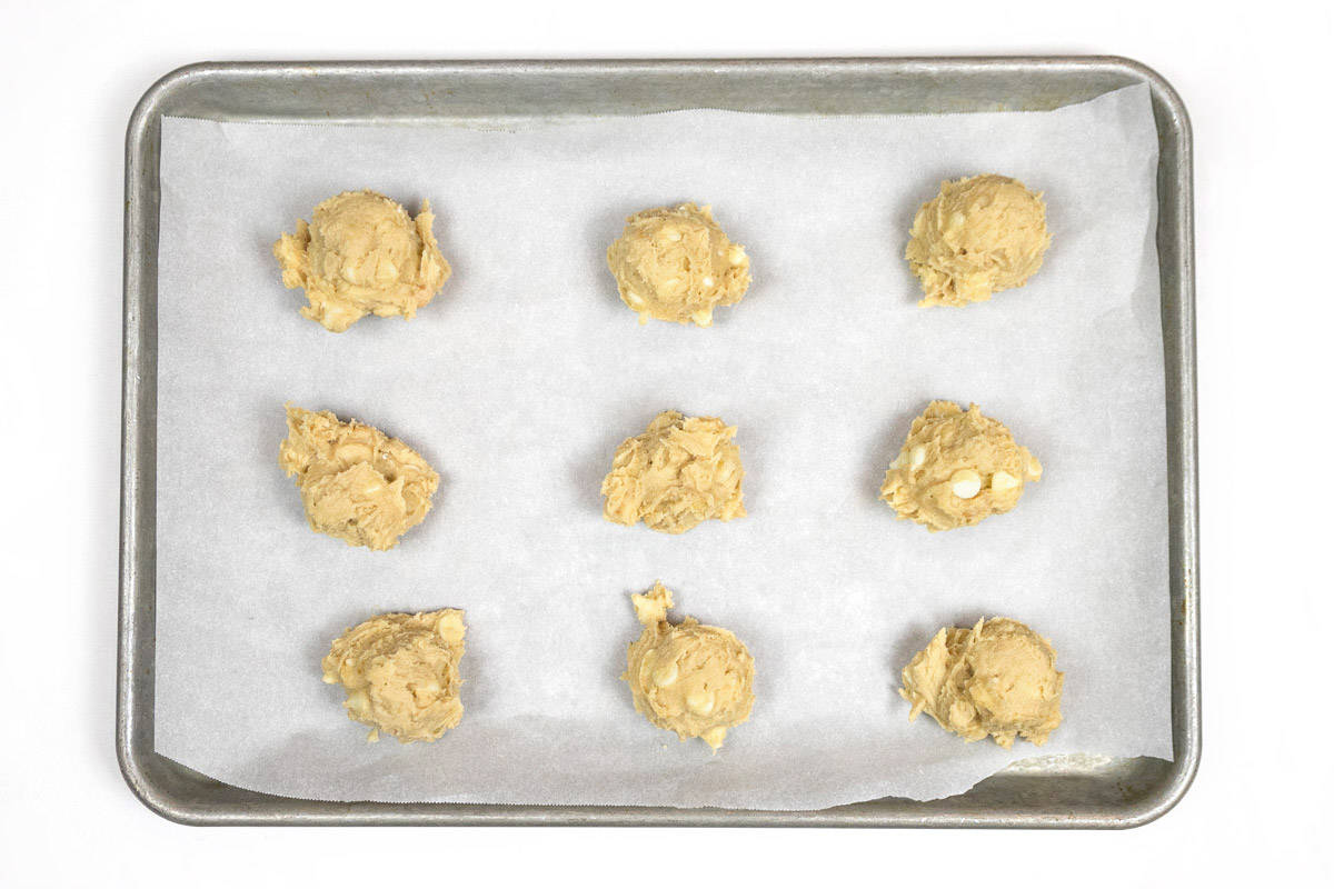 Cookie dough balls on a cookie sheet lined with parchment paper.