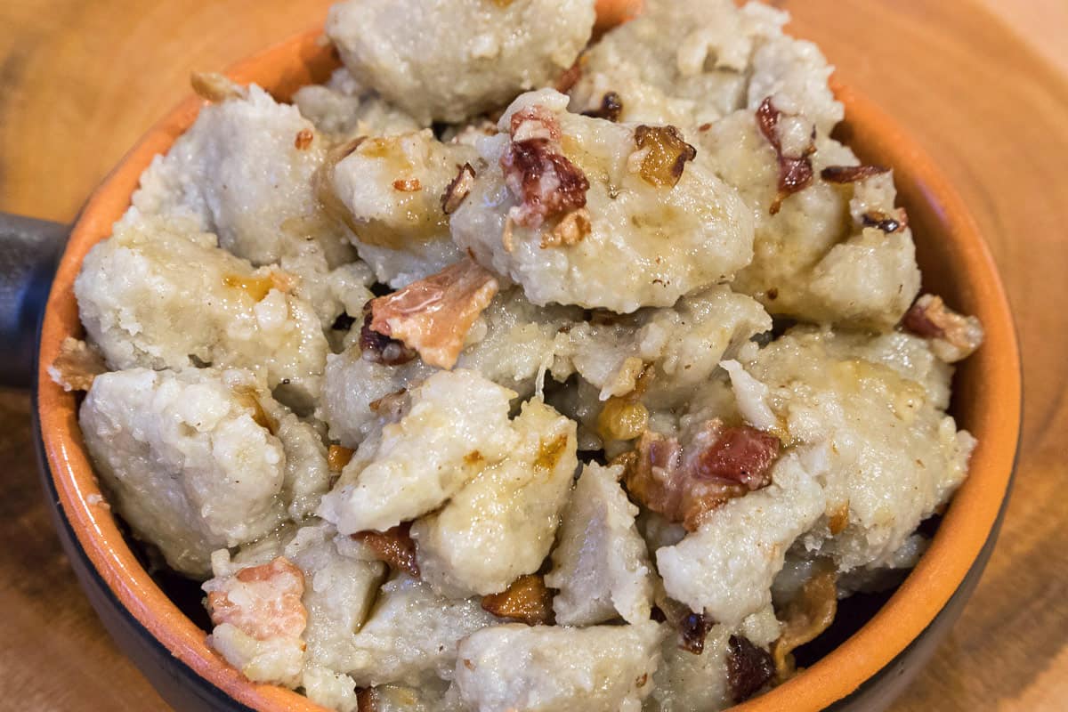 Finished Polish potato dumplings close up in a bowl with bacon.