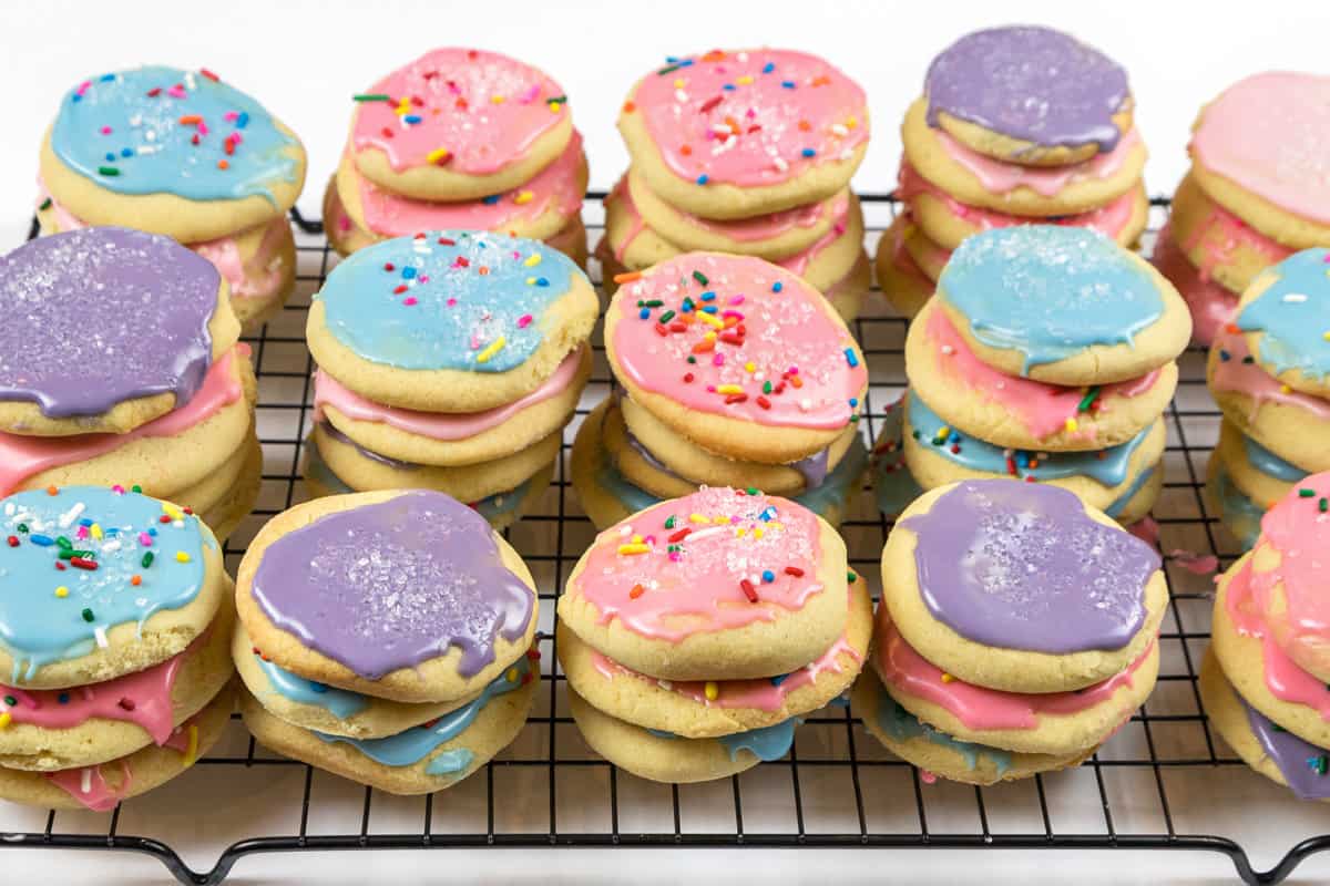 Baked sugar cookies with icing on a wire rack.