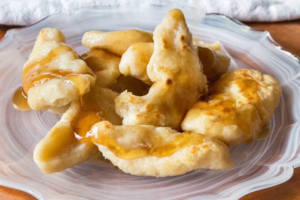 Fried dumplings with syrup on a plate.