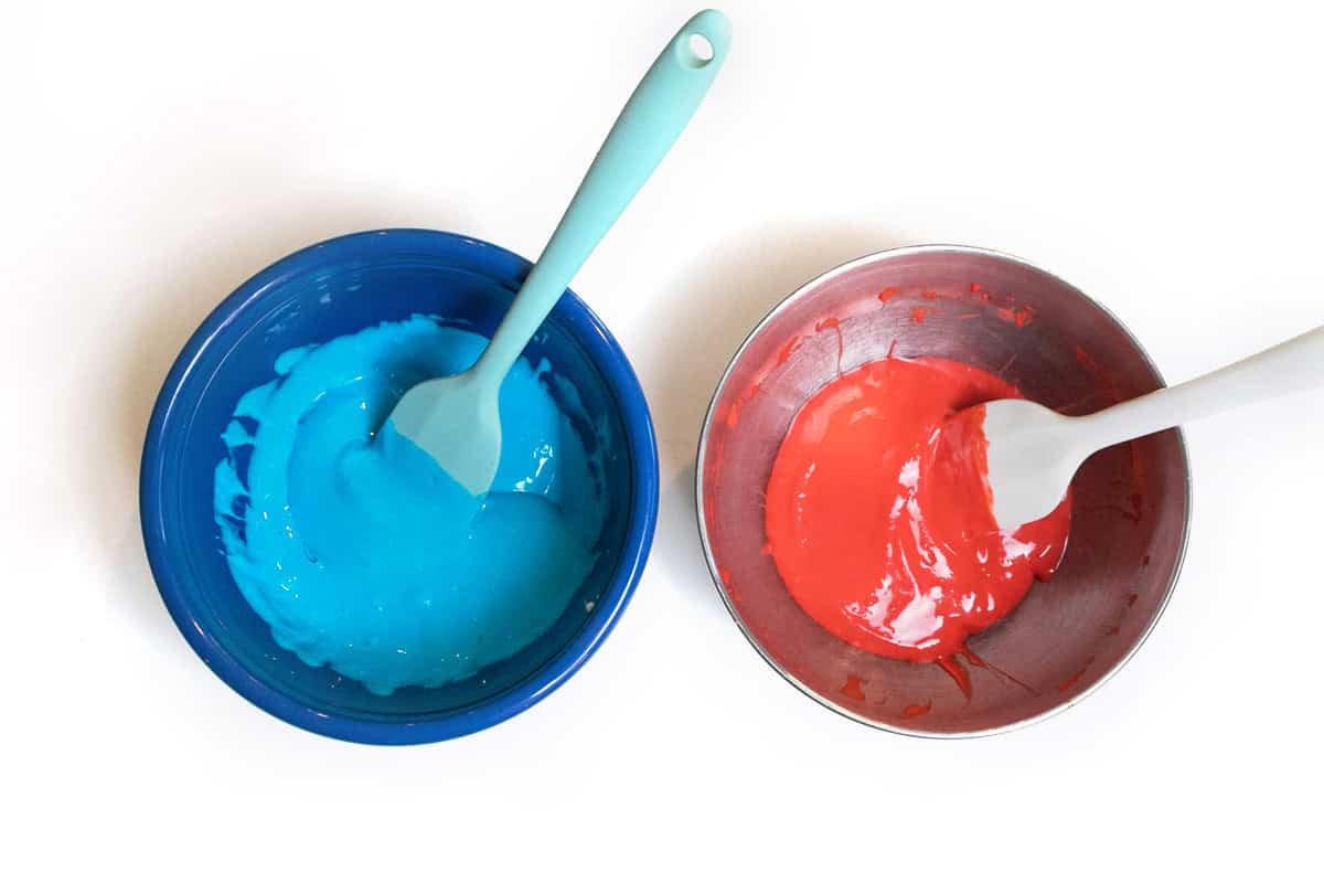 Food coloring and cream cheese mixture in two bowls.