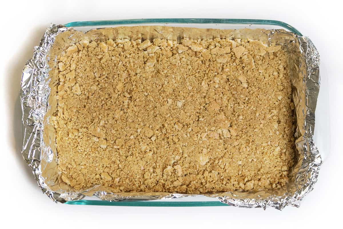 Graham cracker crust in baking dish for 4th of July cheesecake bars.