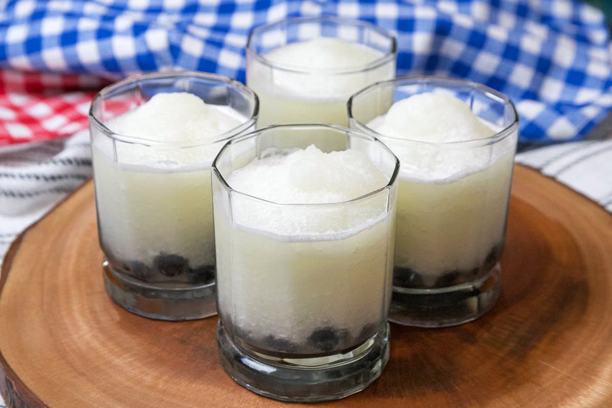 Lemonade is poured into the glasses with blueberries.