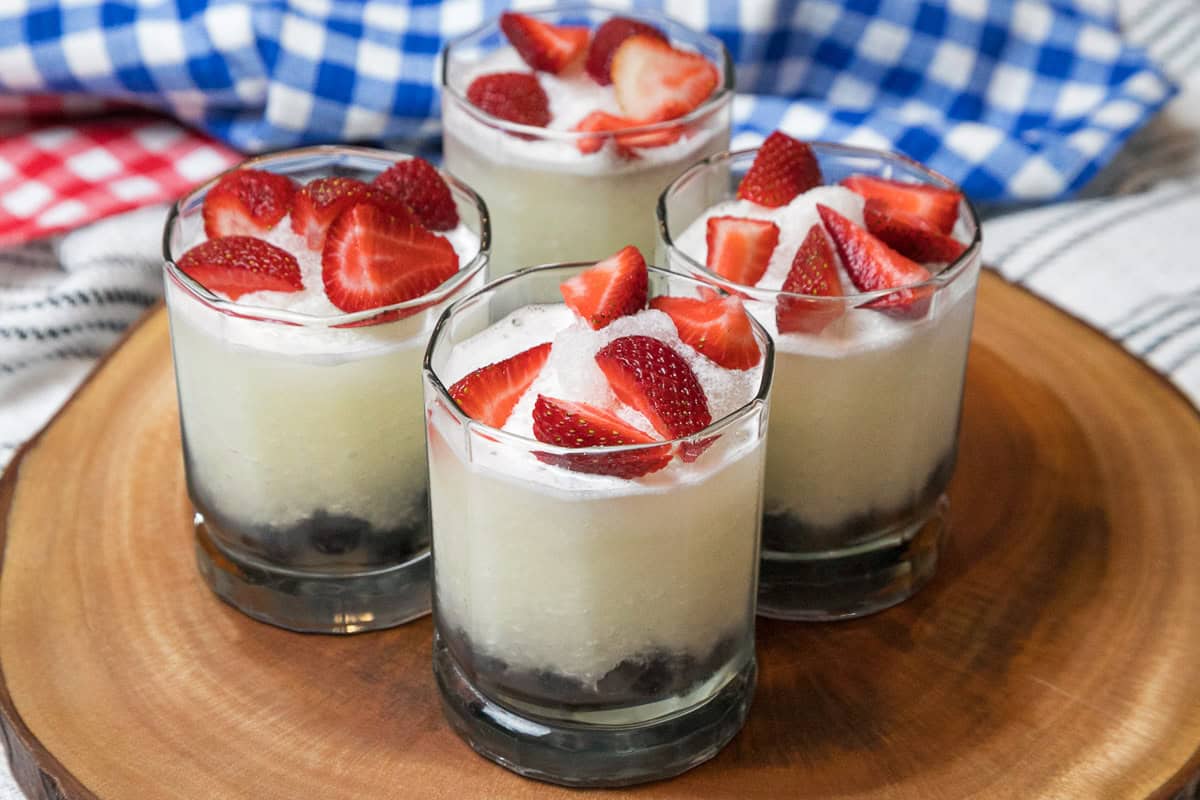 Sliced strawberries are arranged on top of  the lemonade.