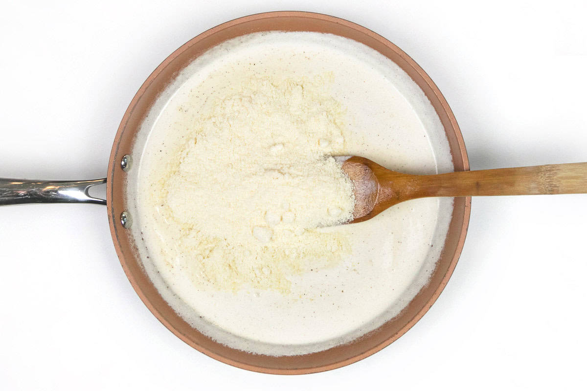 Grated Parmesan cheese, heavy cream, black pepper, minced garlic, and unsalted butter in a skillet.