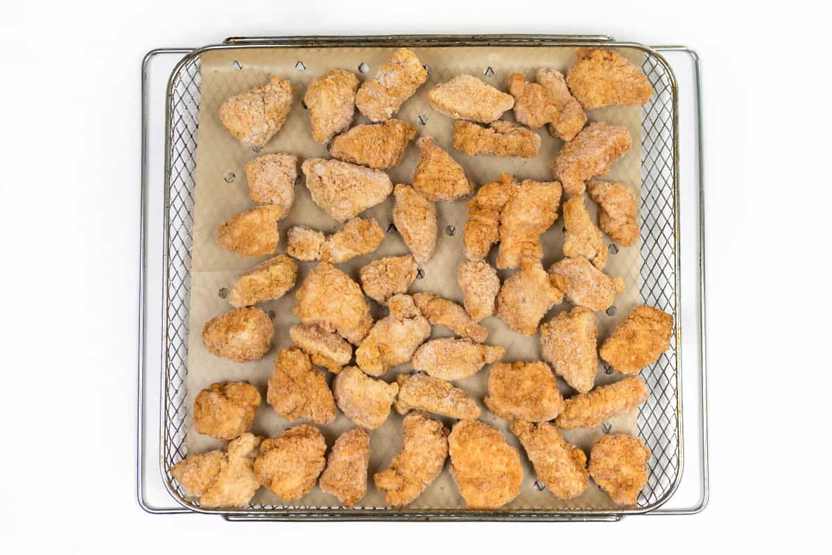 Breaded chicken breast chunks on the air fryer tray.