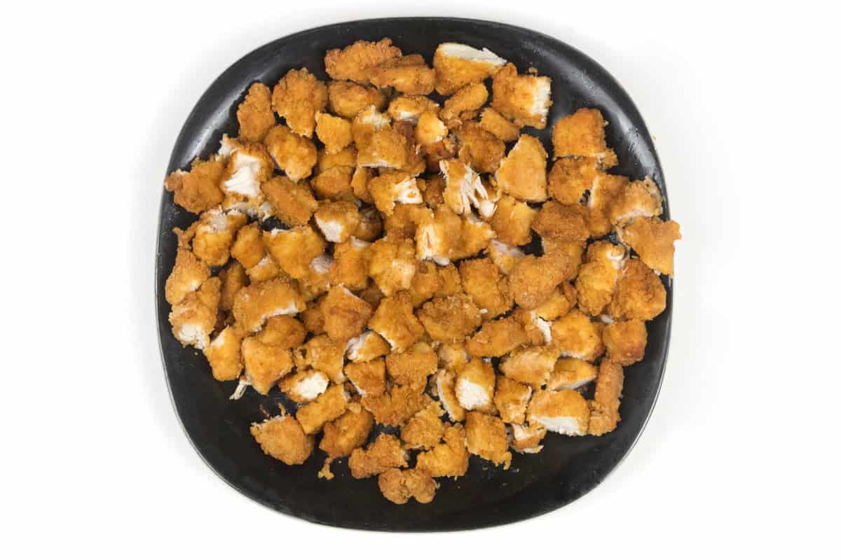 Air fried lightly breaded chicken breast chunks cut in half on a plate.