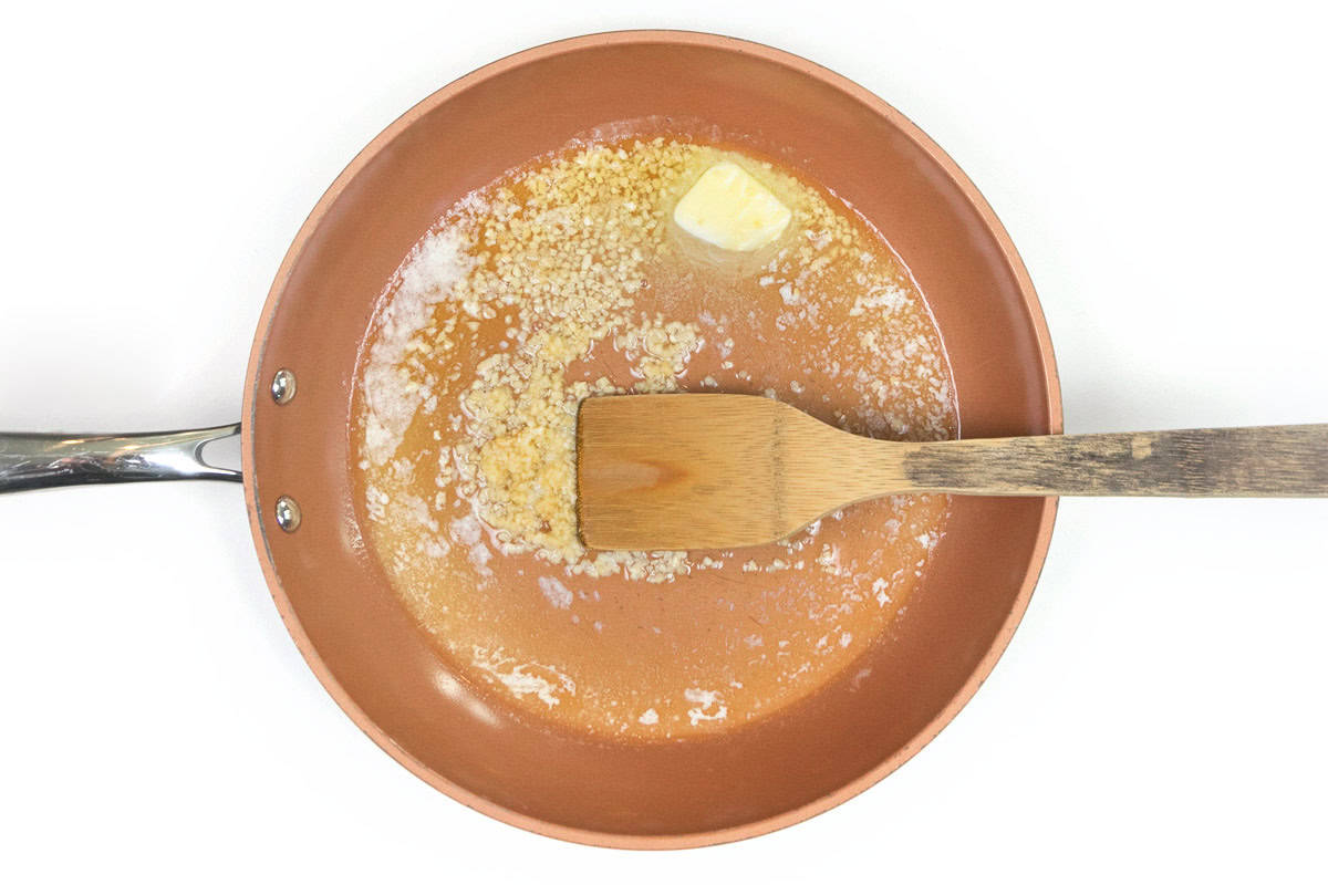 Butter and minced garlic are sautéing in a large skillet.