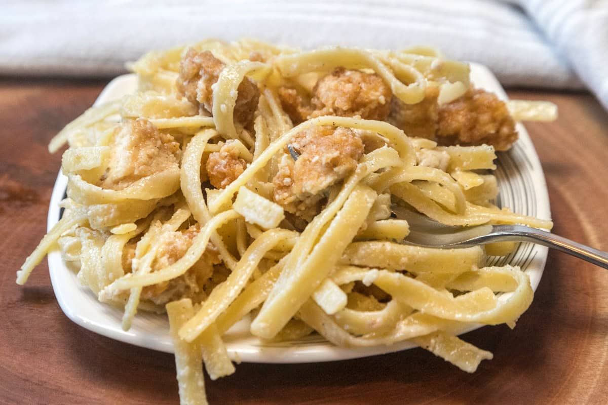 A serving of crispy chicken fettuccine Alfredo on a plate.