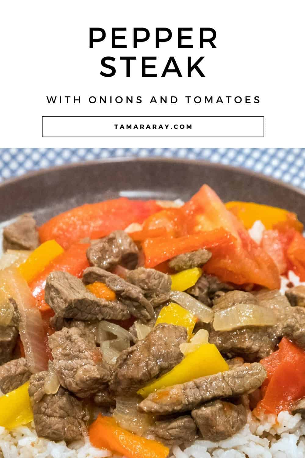 Pepper steak with onions and tomatoes on a bed of white rice.