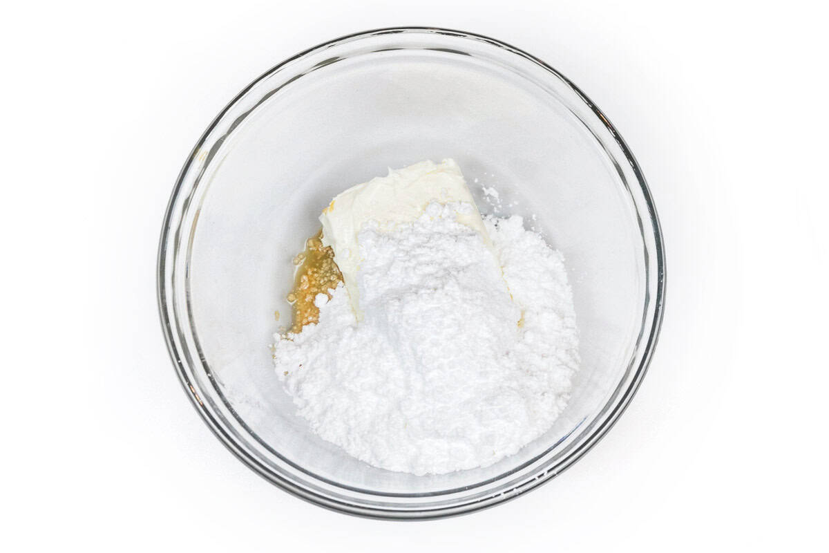 Softened cream cheese, powdered sugar, and vanilla extract in a bowl.