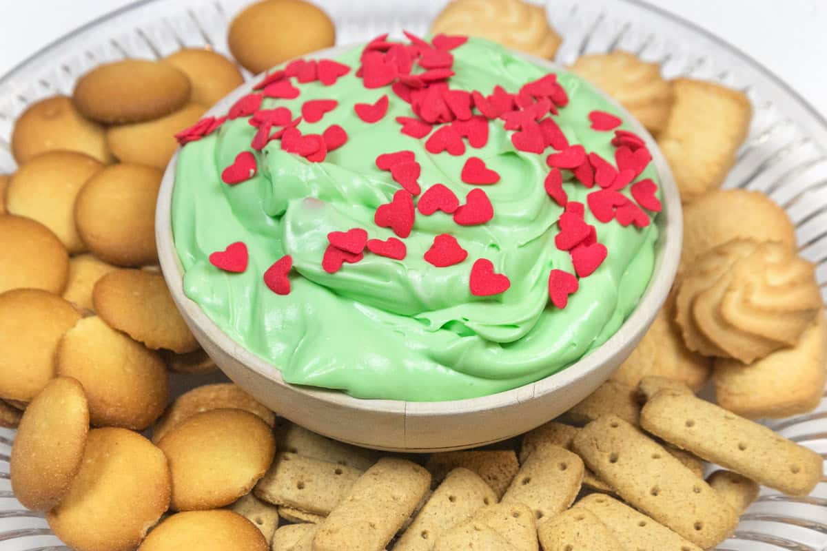 Grinch dip is served on a plate with cookies.