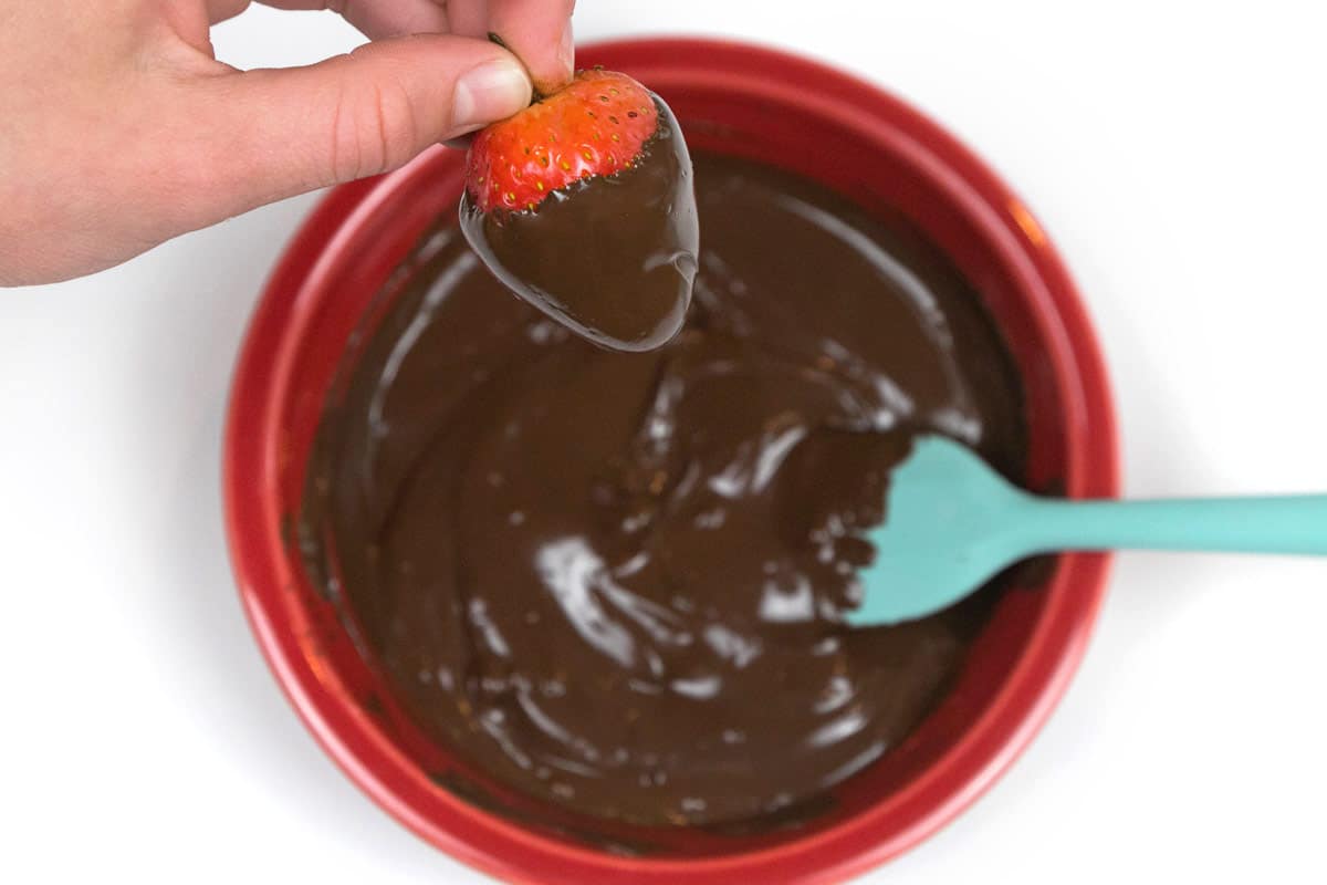 Dip a strawberry into the melted chocolate.