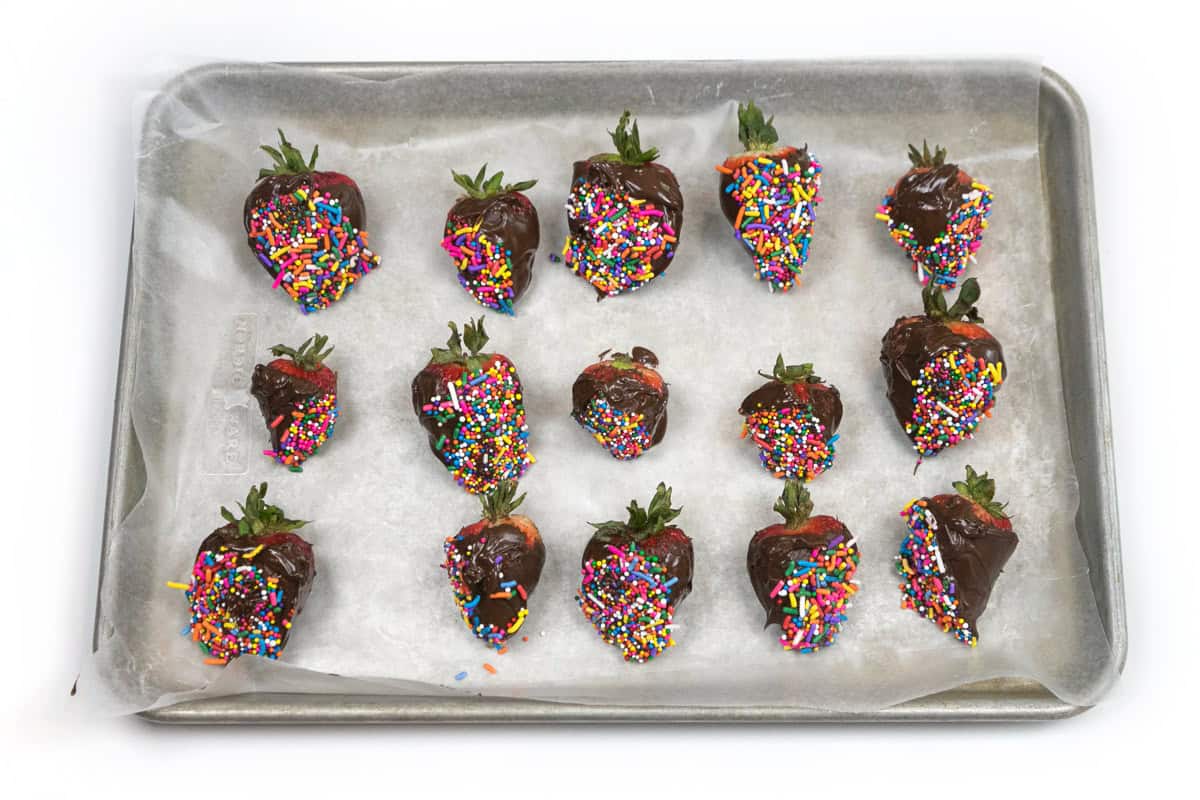 Chocolate covered strawberries with sprinkles on a baking sheet lined with parchment paper.