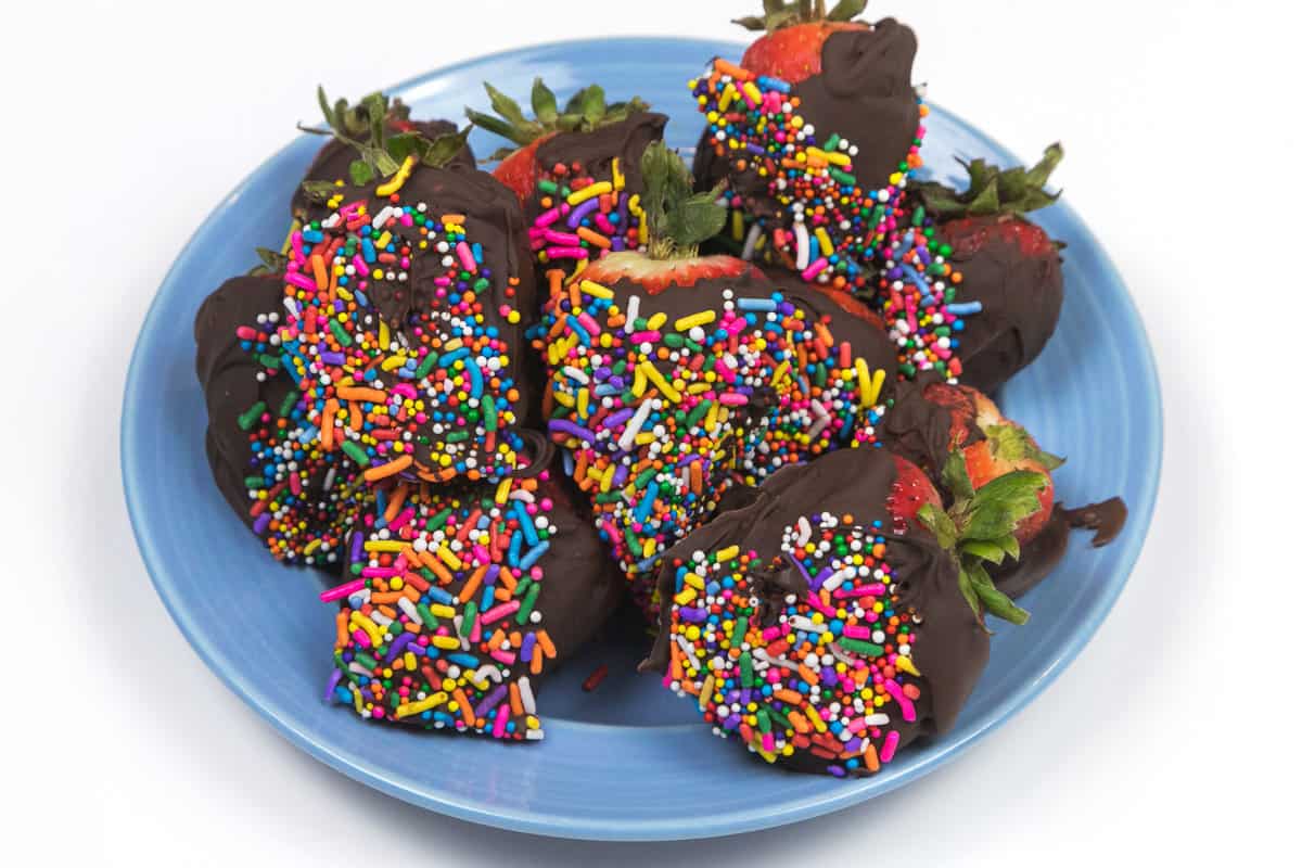Chocolate covered strawberries with sprinkles on a plate.