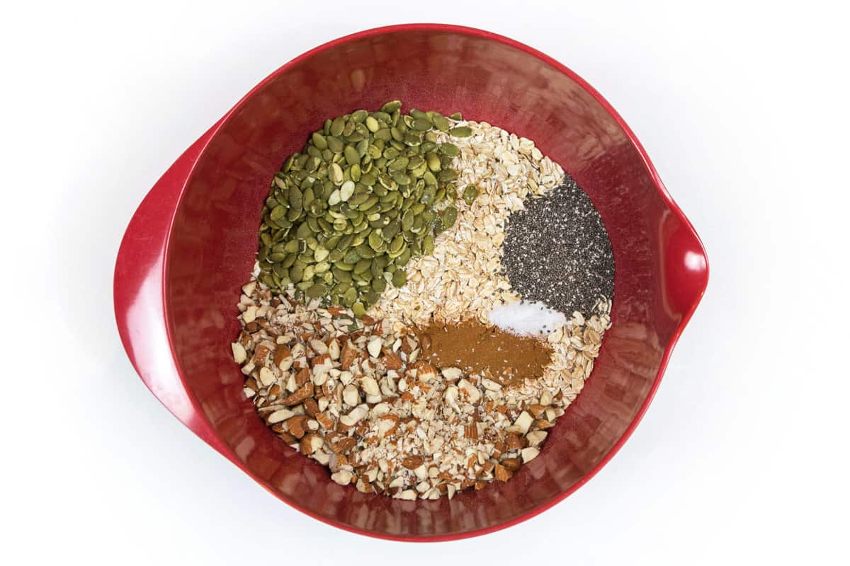 Oats, sliced almonds, pumpkin seeds, chia seeds, cinnamon, and salt in a bowl.