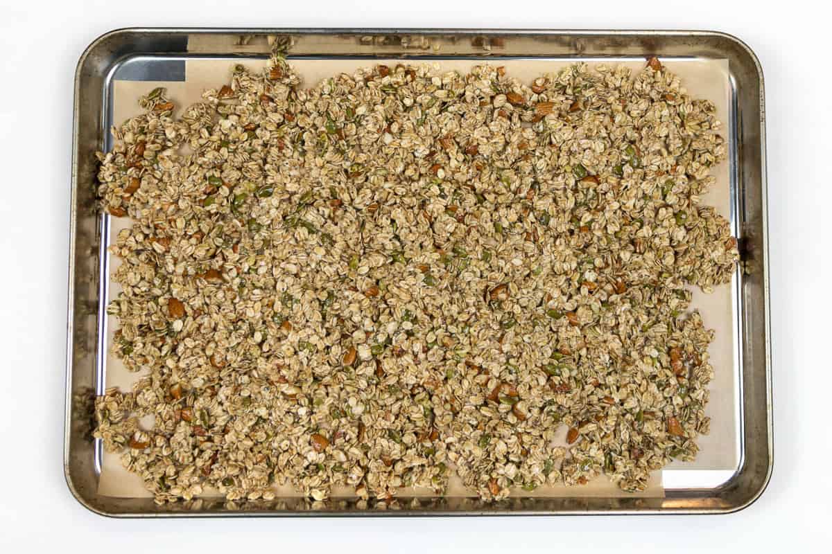 Almond granola with honey mixture on a cookie sheet lined with parchment paper.