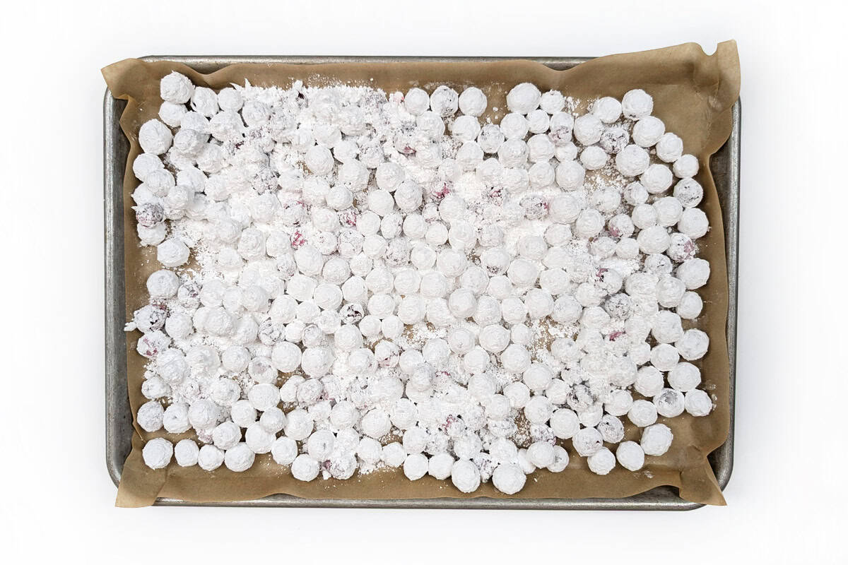 Powdered sugar cranberries spread on parchment paper.