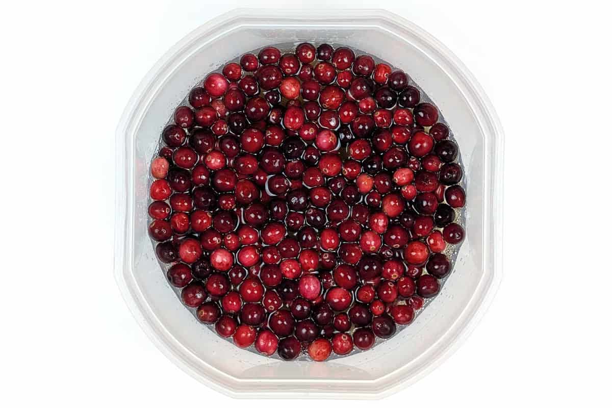 Fresh cranberries, soda pop, and apple cider juice in a bowl.