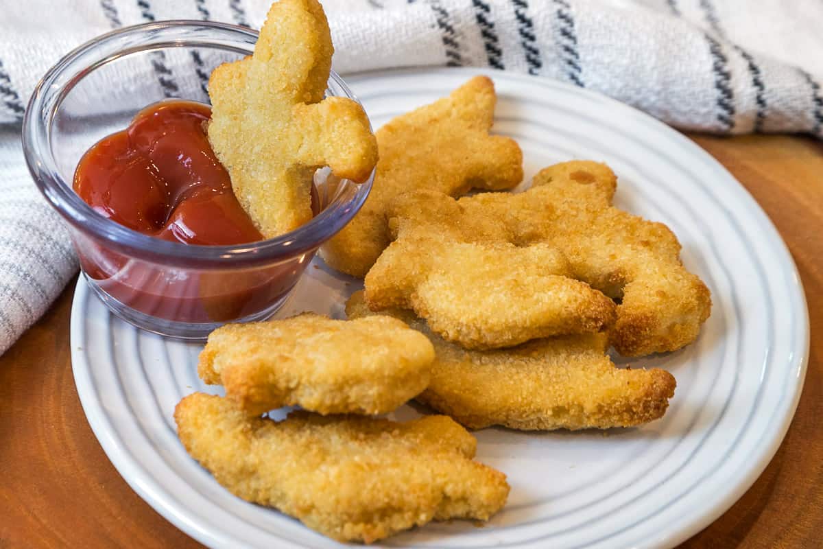 Eight air fryer Dino nuggets on a plate.