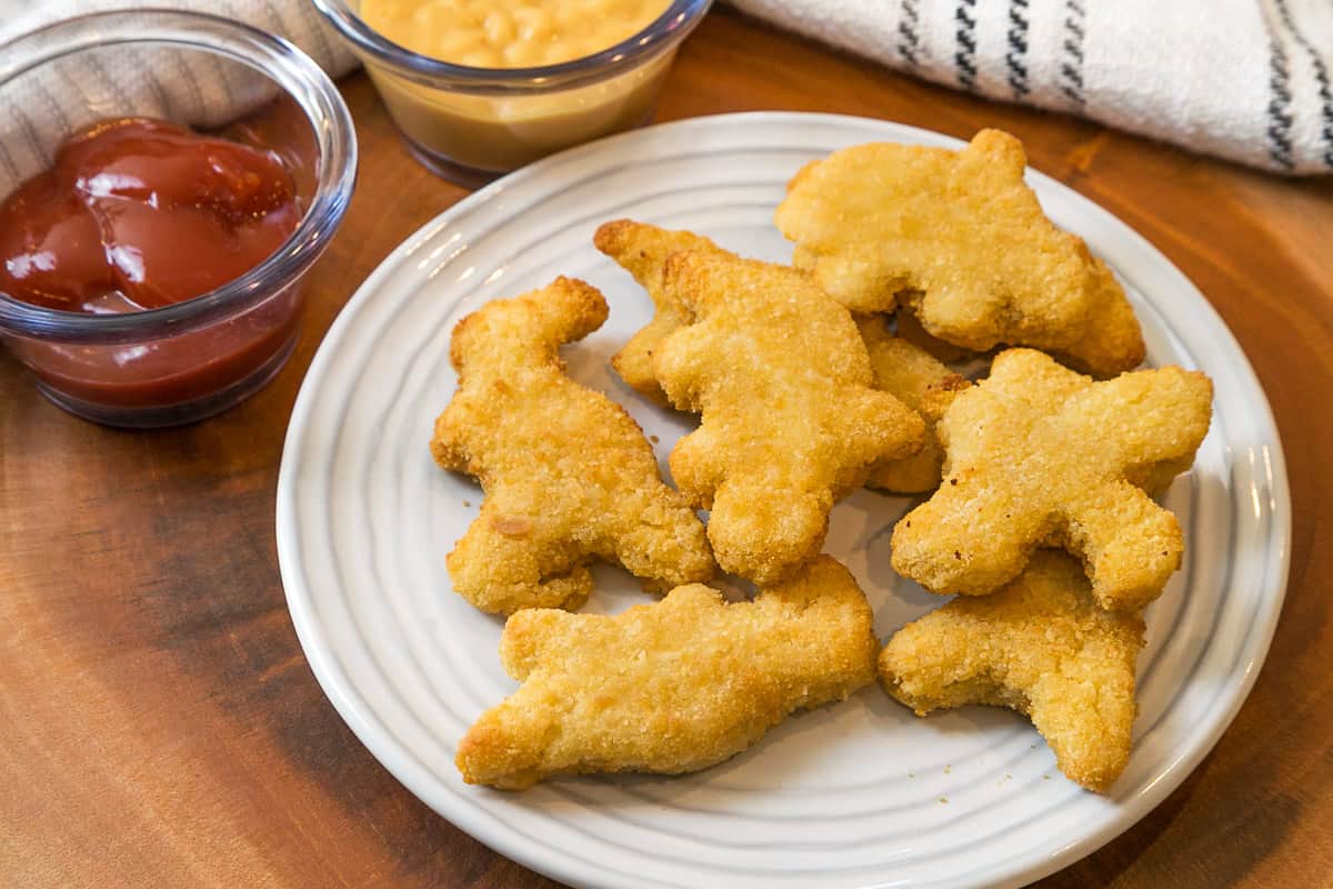 Eight air fryer Dino nuggets on a plate.