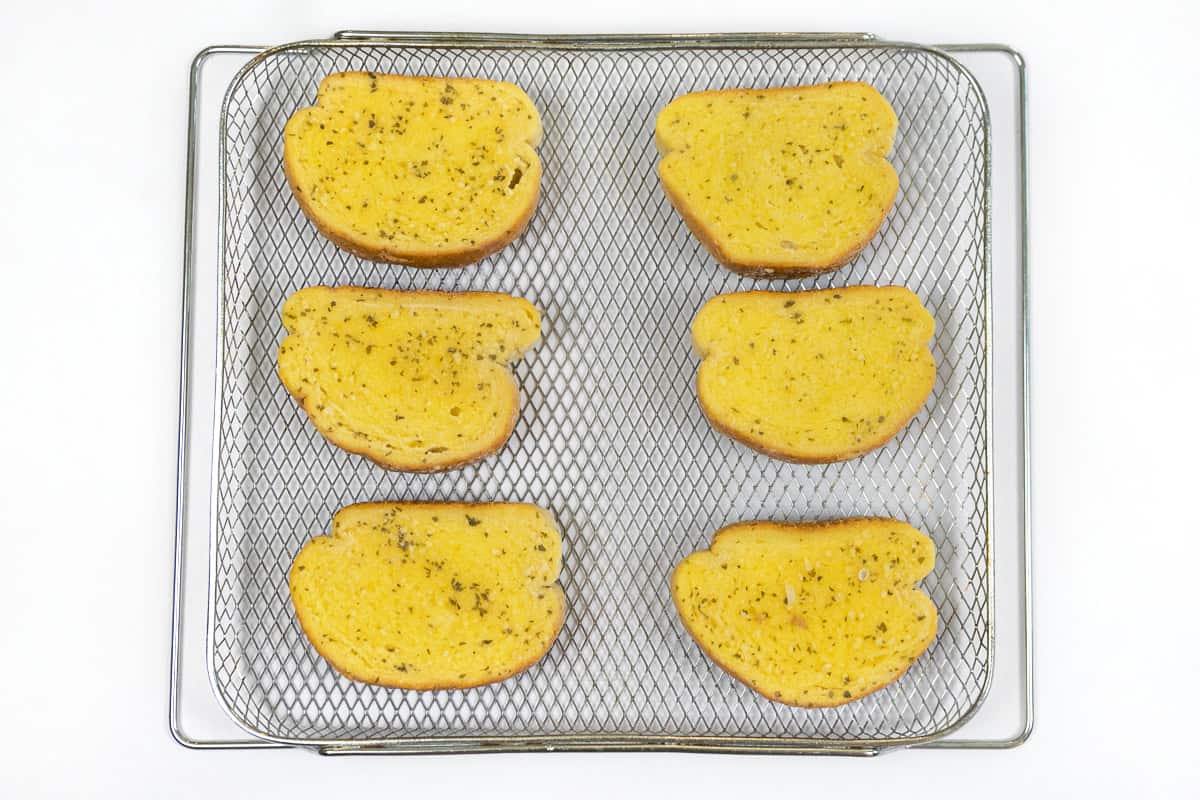 Frozen garlic bread on the air fryer basket.