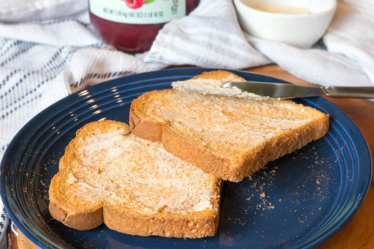 Two slices of toast with butter on a plate.