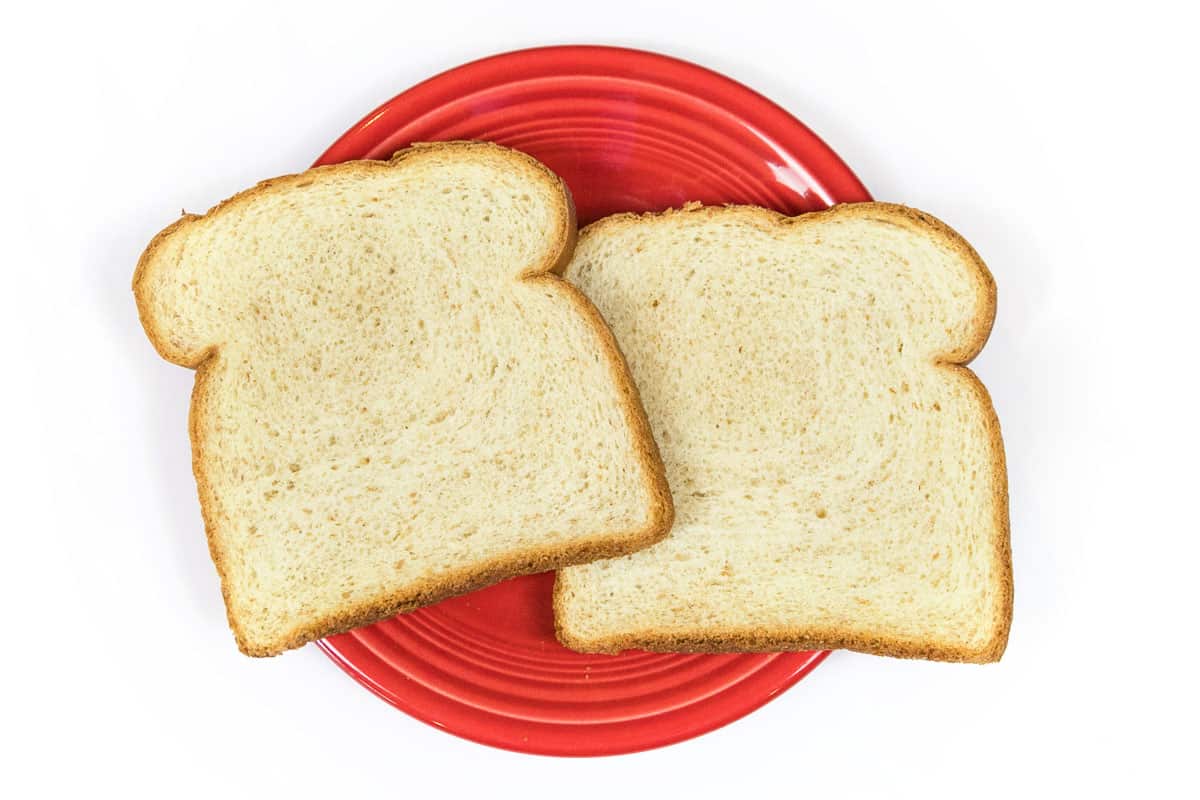 Two slices of bread on a plate before toasting.