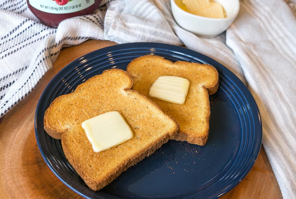 Two slices of air fryer toast with butter on a plate.