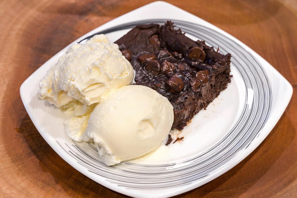 Fudgy avocado brownies with two scoops of vanilla ice cream.