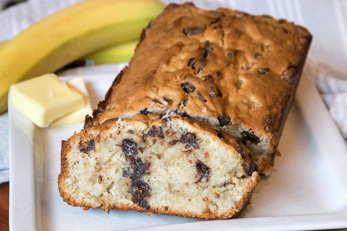A slice of banana bread with cream cheese and chocolate chips on a plate.