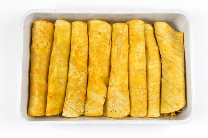 Eight rolled up beef enchiladas in a baking dish.