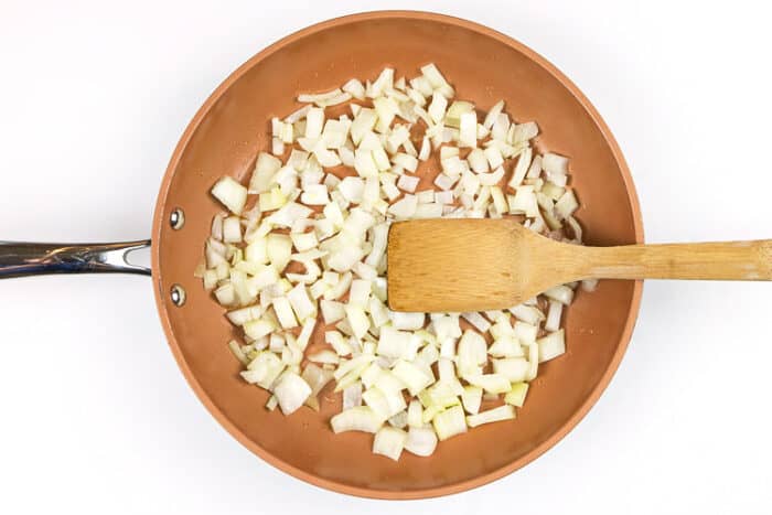 Chopped onions are in a frying pan with one tablespoon of olive oil.