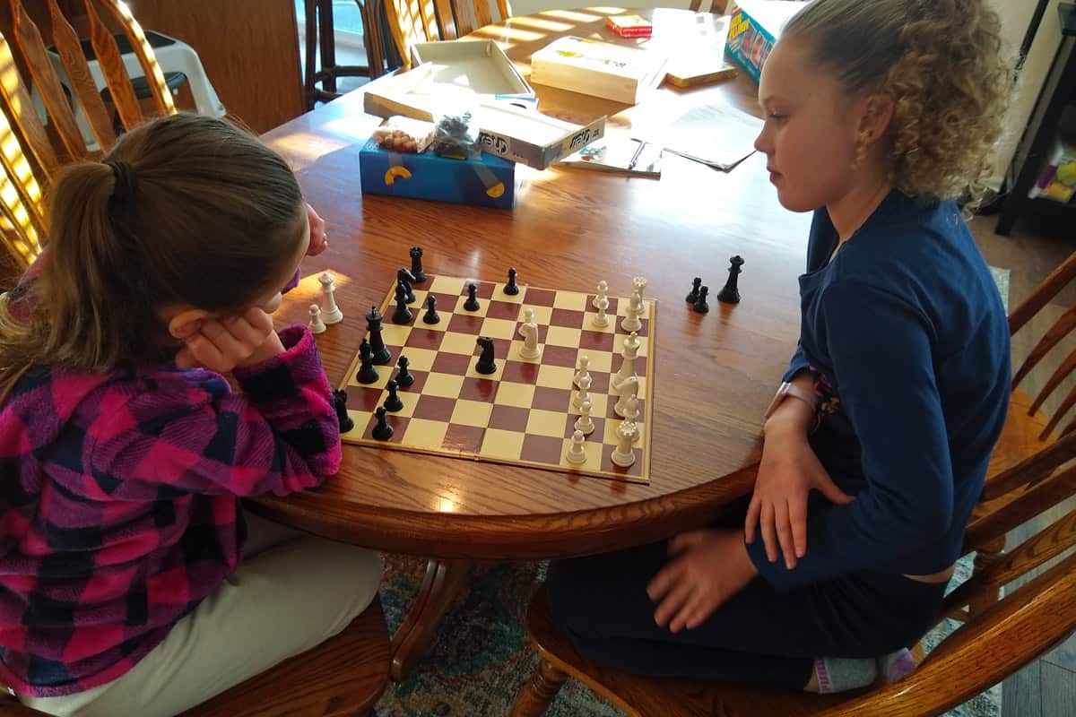 Kids playing board games, specifically chess, at the table.