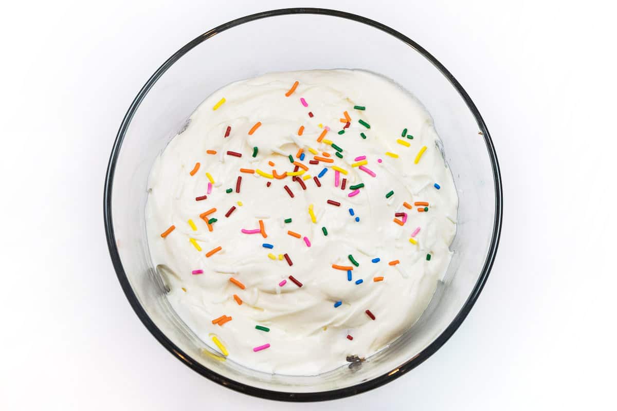 For the second layer, spread half of the cheesecake cream cheese pudding mixture over the top of the cake pieces and then shake sprinkles on top.