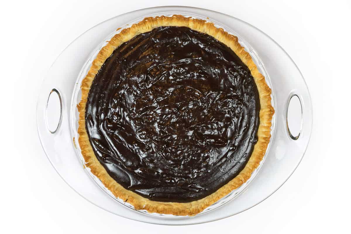 The thickened chocolate filling is poured into the baked pie crust.