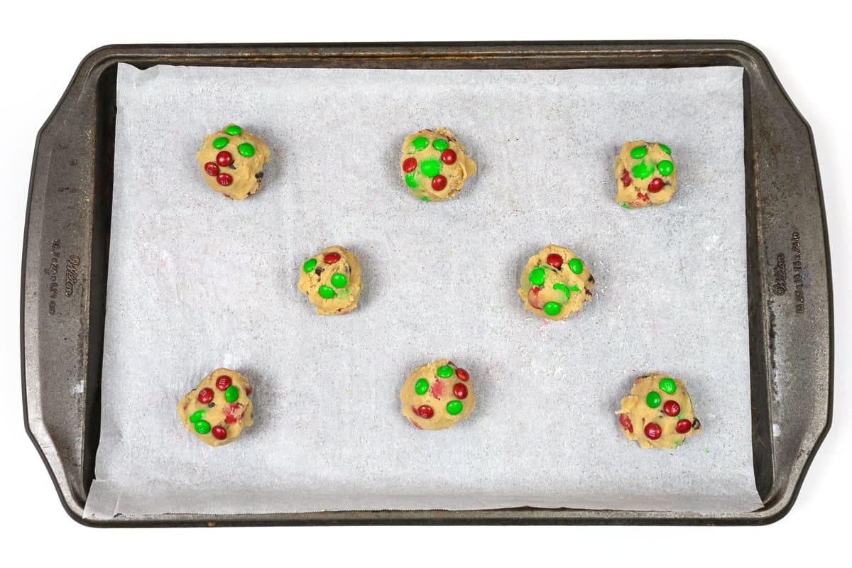 Cookie dough balls on a cookie sheet with parchment paper.